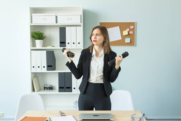 Концепция офиса, фитнеса и людей - Бизнес-женщина, работающая и занимающаяся спортом в своем офисе
 - Фото, изображение