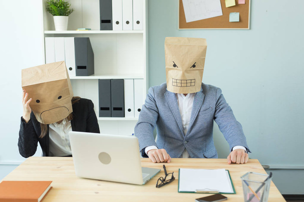 Концепція бізнесу, емоцій та людей - жінка та чоловік носять пакети на голові з зображеними емоціями гнів та страх
 - Фото, зображення