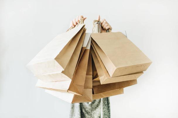 Black Friday sales discount concept. Young woman hold craft paper bags with word Sale on white background. - Foto, Imagen