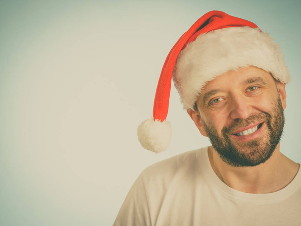Bearded man wearing santa claus hat portrait, on blue with copy space. Christmes time. - Fotografie, Obrázek