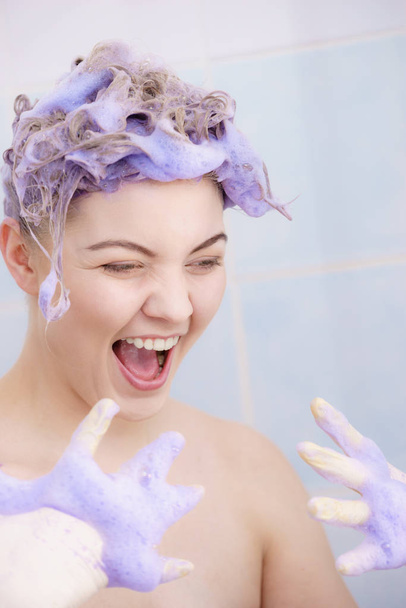 Woman applying coloring shampoo on her hair. Female having purple washing product. Toning blonde color at home. - Fotoğraf, Görsel