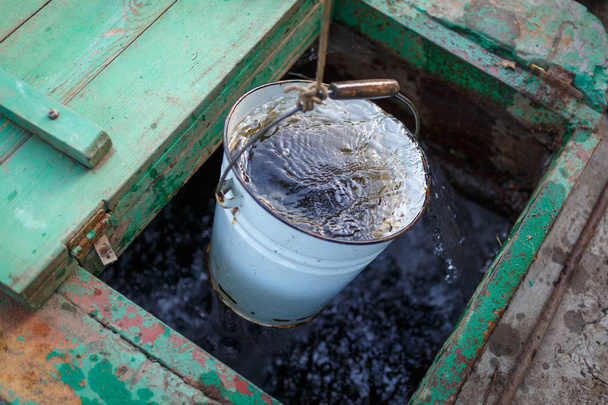 Il secchio pieno di acqua limpida sale dal pozzo profondo
 - Foto, immagini
