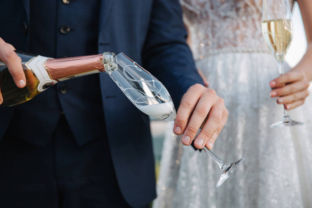 Groom pouring champagne into a glass - Foto, afbeelding