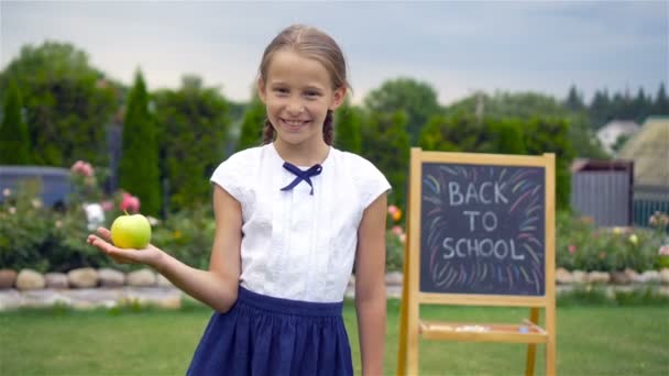 Ευτυχισμένος μικρή μαθήτρια με ένα μαυροπίνακα εξωτερική - Πλάνα, βίντεο