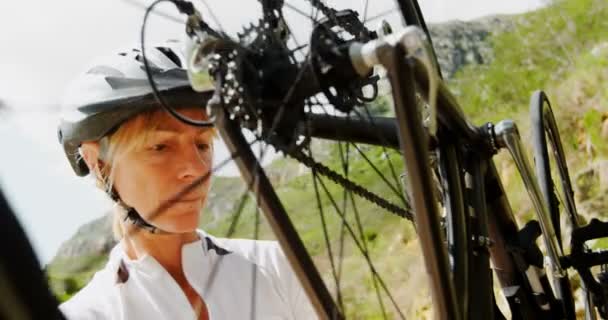 Active senior cyclist checking bicycle at countryside 4k - Filmati, video