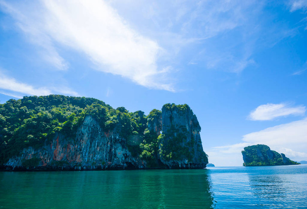 LIMESTONE ISLAND IN ANDAMAN SEA OF THAILAND , BLUE SKY CLOUD SUNNY DAY IN BACKGROUND - Foto, afbeelding