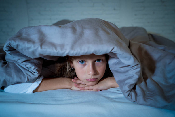Cute little caucasian girl lying in bed covering her head with blanket feeling exhausted and sleepless suffering from insomnia Depression Stress in Children Emotional and Sleeping Disorders concept. - Foto, imagen