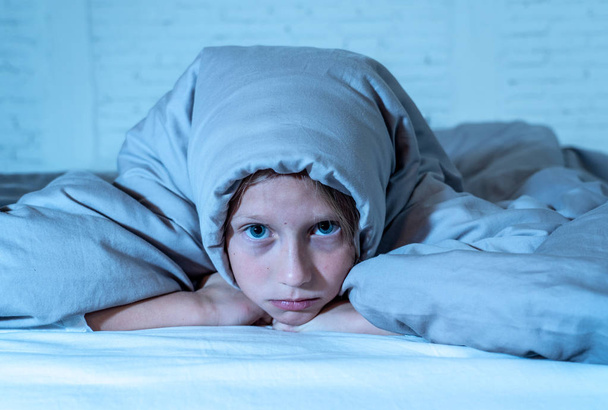 Cute little caucasian girl lying in bed covering her head with blanket feeling exhausted and sleepless suffering from insomnia Depression Stress in Children Emotional and Sleeping Disorders concept. - Фото, изображение