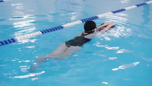 μαθήματα κολύμβησης για παιδιά στην πισίνα - όμορφη κοπέλα με ανοιχτόχρωμο δέρμα που κολυμπά στο νερό - Πλάνα, βίντεο