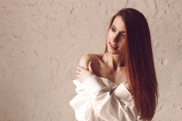 Portrait of attractive young redhead woman with long hair sitting in man s shirt touching herself for naked shoulder - Fotoğraf, Görsel