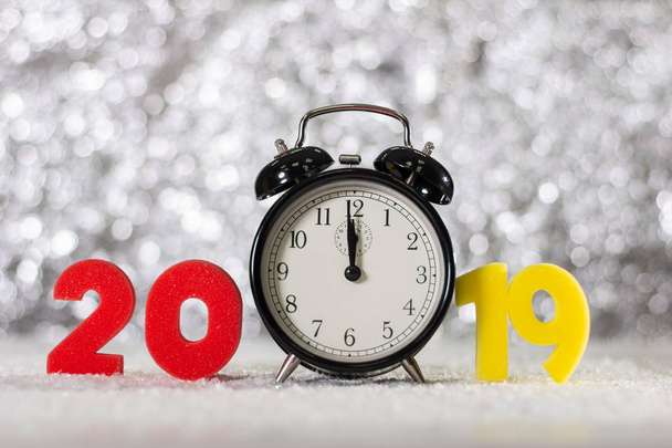 Номер 2019 цифр и будильник на фоне праздничных огней. Концепция нового 2019 года
. - Фото, изображение