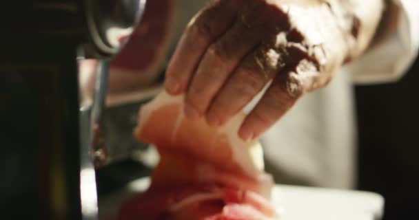 young but experienced slices Parma ham Italian very fine and he savored the taste and goodness of italy, the parma ham is cutted by a professional machine in dark ambient with shadows - Filmagem, Vídeo