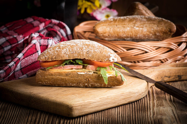 Trójkątna kanapka z serem, szynką i pomidorem na drewnianym stole. - Zdjęcie, obraz