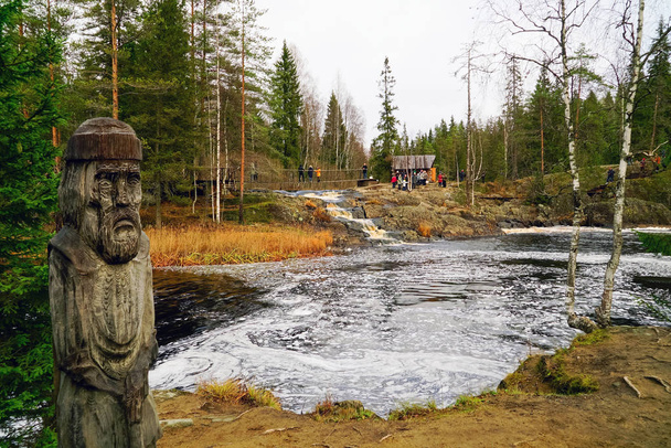 Резная деревянная скульптура старика у водопада на реке Тохмайоки
. - Фото, изображение