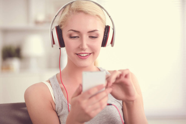 Young beautiful woman at home sitting on sofa and listening music - Foto, Bild