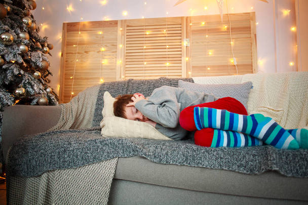Little boy sleeping on the bed at home on Christmas Eve in the New Year decorations - Fotoğraf, Görsel