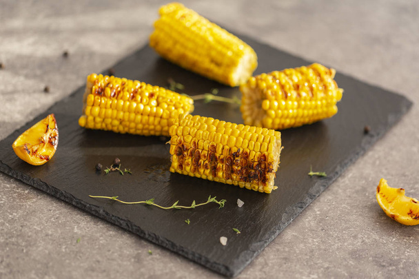 Grilled corn grilled on fire. On a dark stone table. - Foto, afbeelding