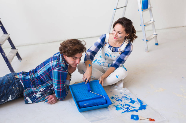 Επισκευή, ανακαίνιση και άνθρωποι έννοια - ζευγάρι που πρόκειται να βάψετε τον τοίχο, ετοιμάζουν το χρώμα και βούρτσες - Φωτογραφία, εικόνα
