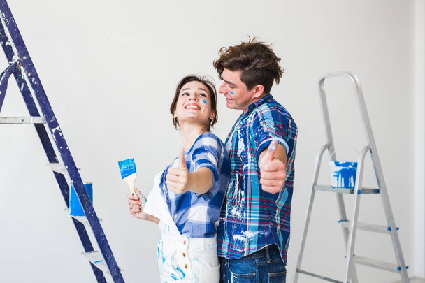 Repair, renovation and people concept - Woman and man gestured thumbs up - Foto, Bild