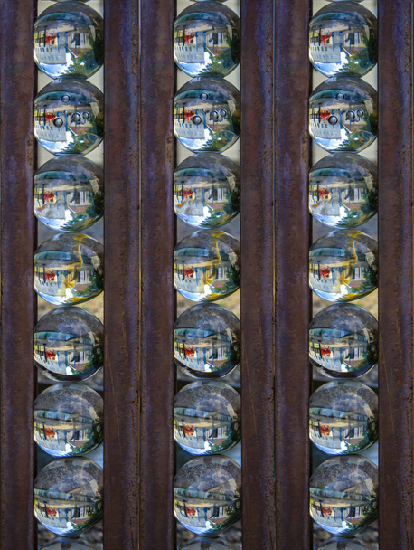 Reihen von Glaskugeln, in denen sich die Umgebung widerspiegelt, Eisenstangen dazwischen - stilisiertes Bild, Ölgemälde - Foto, Bild