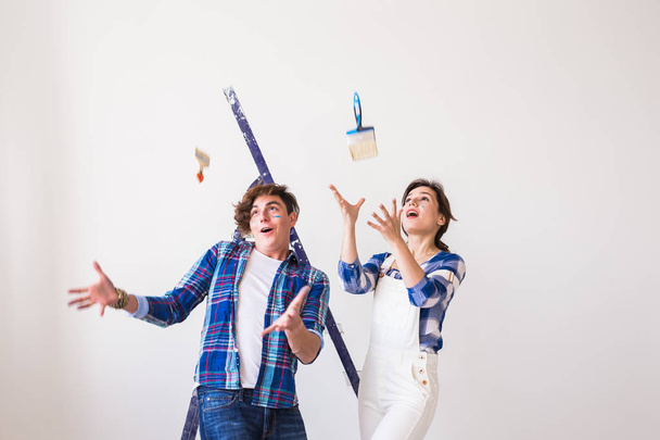 Renovation, redecoration and people concept - Funny handsome man and attractive woman with instruments over white wall background - 写真・画像