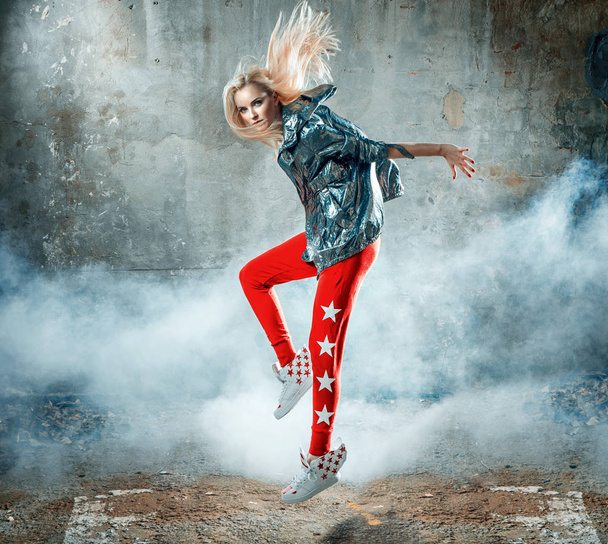 Pretty blond woman dancing in a grungy place full of smoke - Foto, imagen