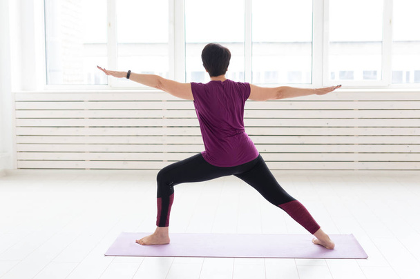 Gente, deporte y concepto de salud - Mujer de mediana edad practicando yoga, de pie en Guerrero dos ejercicios
 - Foto, imagen