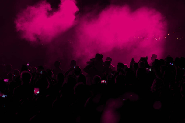 コンサート フィールド、混雑した人々、煙でピンクの舞台照明. - 写真・画像