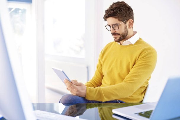 Portrait of casual young businessman holding digital tablet in his hand and wearing casual clothes while working in the office.  - Foto, imagen