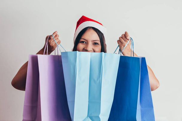 Young woman in santa hat with shopping bags on white background - Фото, зображення