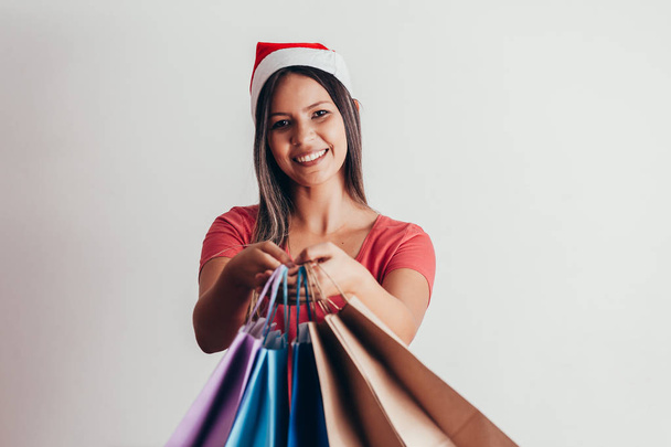 Young woman in santa hat with shopping bags on white background - Foto, Imagem