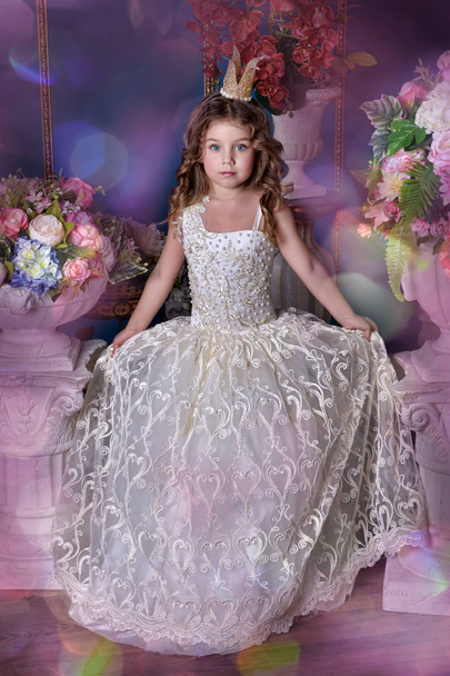 portrait of a little girl princess in a white dress and a crown among flowers - Foto, Imagen
