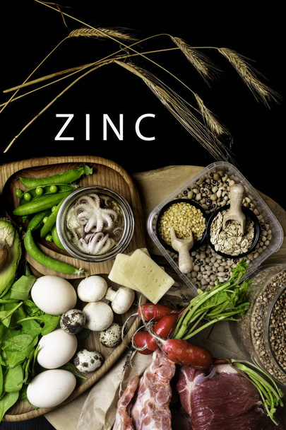 Potraviny nejvyšší v zinku jako chobotnice v ropy, hovězí, pohanka, lutý sýr, špenát, avokado, hrášek, houby, fazole, ředkvičky vejce s nápisem zdravá dietní potraviny pohled shora - Fotografie, Obrázek