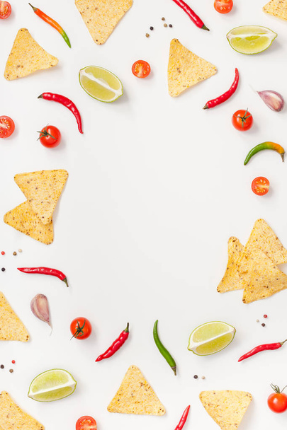 kreative Draufsicht flach lag von frischen mexikanischen Lebensmitteln Zutaten mit Tortilla Nachos Chips Knoblauch Pfeffer Limetten Tomaten auf weißem Tischhintergrund mit Kopierraum. Kochkonzept für die Zubereitung von Lebensmitteln - Foto, Bild
