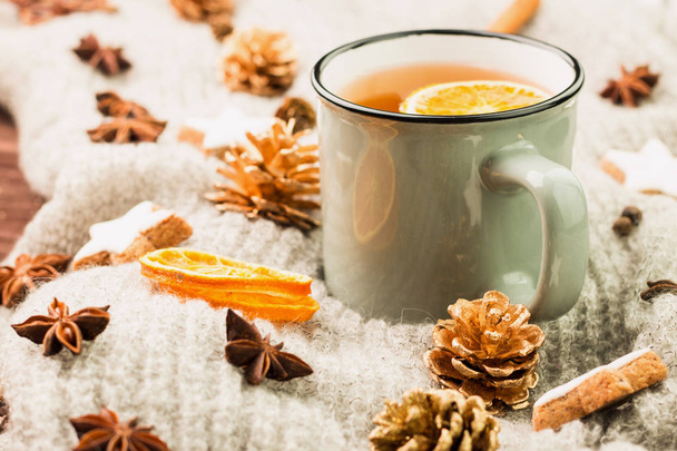 Χειμώνας και το νέο έτος θέμα. Χριστουγεννιάτικο τσάι με μπαχαρικά, φλιτζάνι τσάι με πορτοκάλι, κανέλα, γλυκάνισο, μπισκότα σε σχήμα αστέρι, ελάτου, πιπεριού και γκρίζο κασκόλ σε ξύλινο υπόβαθρο. Χώρο αντίγραφο για το κείμενο. - Φωτογραφία, εικόνα