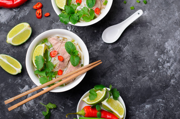 traditionelle vietnamesische Suppe pho bo mit Reisnudeln, Rindfleisch und Kräutern auf dunklem Hintergrund, asiatische Küche - Foto, Bild