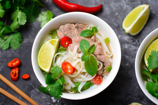 Traditional Vietnamese Soup Pho Bo with Rice Noodles, Beef and Herbs on Dark Background, Asian Cuisine - Foto, Bild
