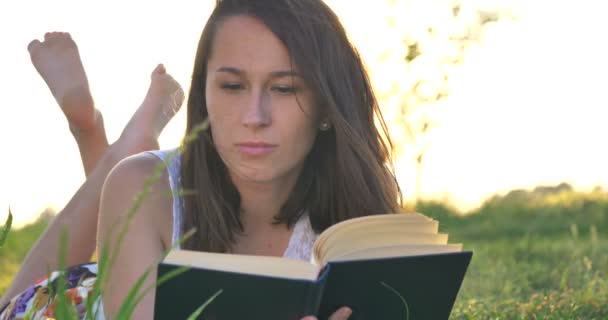 video of woman lying on green field meadow and reading book  - Video