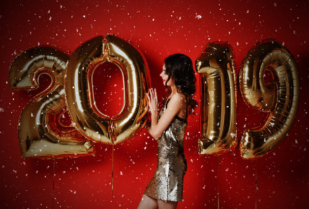 Portrait Of Beautiful Smiling Girl In Shiny Golden Dress Throwing Confetti, Having Fun With Gold 2019 Balloons - Foto, imagen