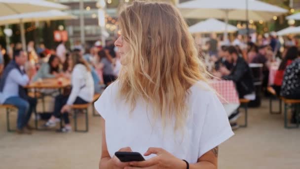 Hipster teenager at festival uses smartphone - Materiał filmowy, wideo