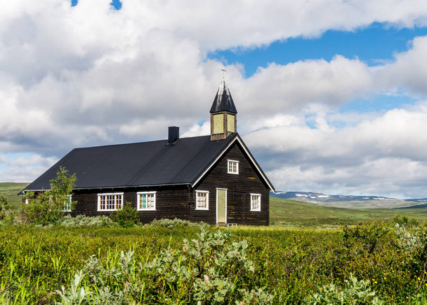 Wooden church on a green meadow against a background of a cloudy sky, Finnmark, Norway - Foto, Imagen