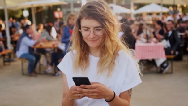 Hipster teenager at festival uses smartphone - Кадры, видео