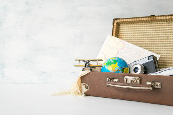 Viajes, aventura, concepto de vacaciones. Maleta retro marrón con juego de cuadernillos de viaje, mapas, cámara, ropa y avión de juguete. Cómo hacer las maletas. Explorar: Vacaciones de aventura
 - Foto, Imagen