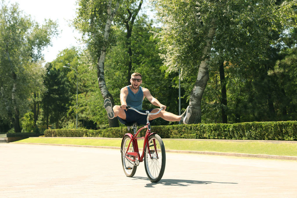 Attractive man riding bike outdoors on sunny day - Foto, afbeelding