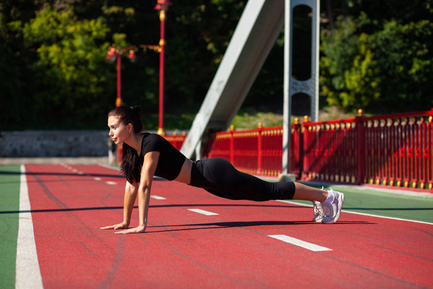 Kobieta młody sportowiec brunetka robi deski ćwiczeń odkryty na moście - Zdjęcie, obraz