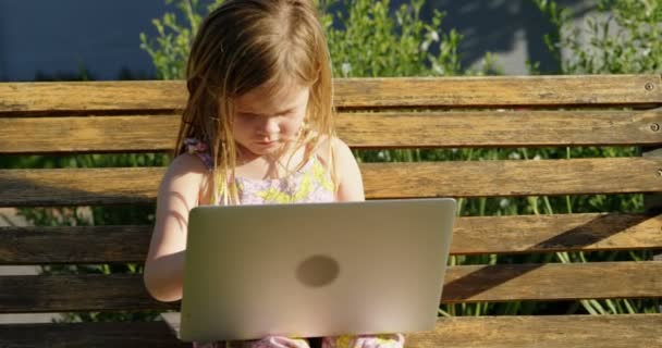 Innocence girl using laptop in the garden 4k - Filmati, video
