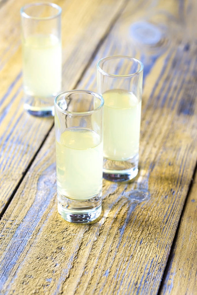 Three glasses of limoncello on the wooden background - Photo, Image