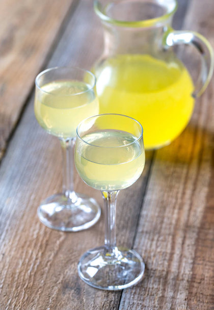 Two glasses of limoncello on the wooden background - Foto, imagen