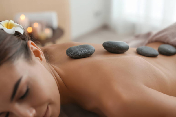 Beautiful young woman getting hot stone massage in spa salon - Foto, imagen