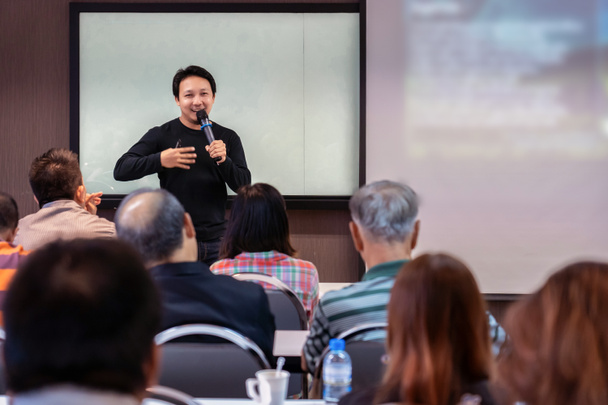 Asian Speaker or lecture with casual suit on the stage in front of the room presenting with the screen in the conference hall or seminar meeting room, business and education concept - Photo, Image